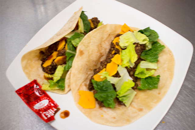 Vegan Lentil Tacos with flour tortillas, Daiya vegan cheddar, lettuce, and Fire sauce