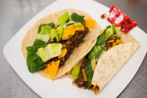 Vegan Lentil Tacos with flour tortillas, Daiya vegan cheddar, lettuce, and Fire sauce